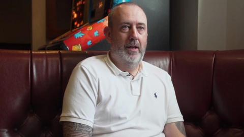 Mark Williams seated on a sofa