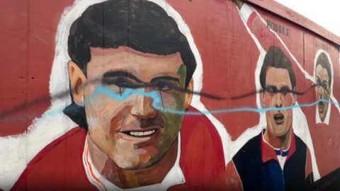 A mural of three football players with blue and black paint daubed over their eyes and just above their mouths.