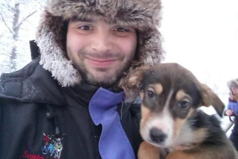 Bernard Mongan posing for a photo with a dog. Mr Mongan is wearing a fluffy hat.