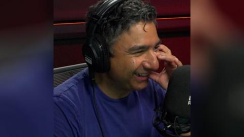 Nick Mohammed smiles in front of a microphone