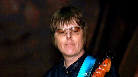 Andy Rourke playing guitar on stage in 2006