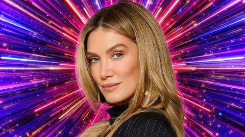 Delta Goodrem in front of a graphic showing numerous purple, pink and blue lines radiating from the centre, in a Strictly promotional photo