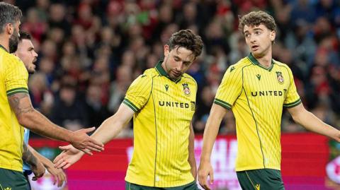 Wrexham players Harry Ashfield and Lewis Brunt celebrate a goal by shaking hands with team-mates