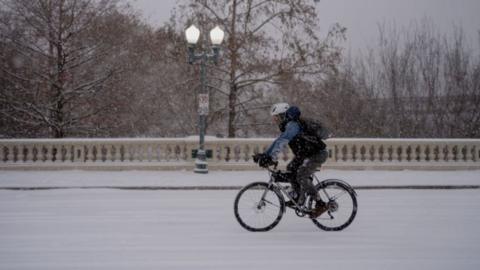 A man bikes along Sabine Street Bridge near downtown as winter storm Enzo brings heavy bands of snow and sleet on January 21, 2025 in Houston, Texas