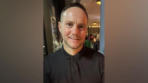 Lee Claydon smiling and wearing a black shirt