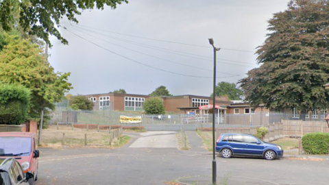 A single-storey flat-roofed brick school building at the end of a cul-de-sac