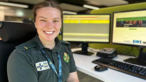 A call handler smiles at the camera from her desk