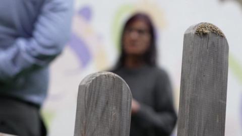 A blurry image of woman wearing a grey jumper.