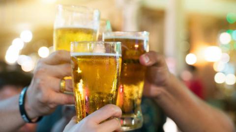 Close up of three hands toasting beer at a bar restaurant.