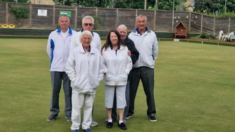 Members of Halls Bowls Club pose wearing whites on their green.