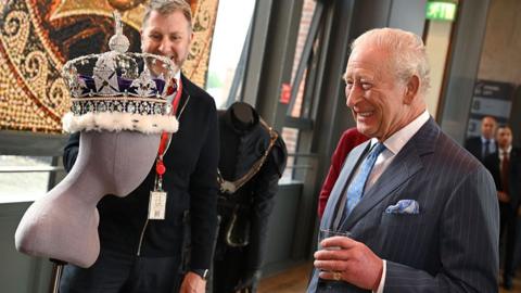King Charles III laughs as he views a replica crown during a tour of costumes during the interval at the Royal Shakespeare Company's performance of The Tempest at the Royal Shakespeare Theatre in Stratford-upon-Avon, England on 22 May 2026.