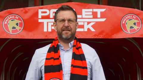 Walsall's new head of football Steward Mairs poses with a club scarf around his neck in front of the tunnel at the Pallet-Track Stadium