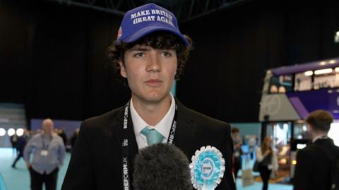 Young man with Make Britain Great Again hat at Reform UK conference