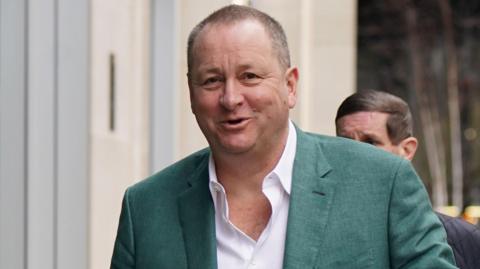British retail entrepreneur Mike Ashley pictured wearing a green suit jacket and white shirt in February 2024
