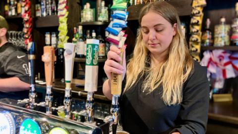 Ruby Caroline-Goodman pouring a pint at a pub bar