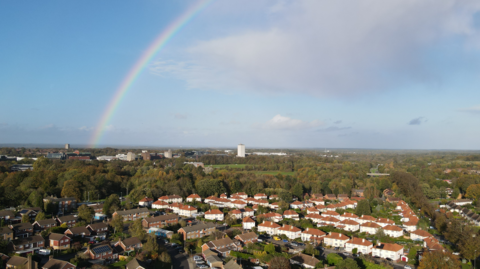 Aerial shot of Basingstoke, a built-up area with lots of houses. There is a rainbow in the sky.