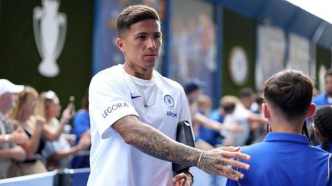 Enzo Fernandez taps a child fan on the back when entering the stadium to play for Chelsea