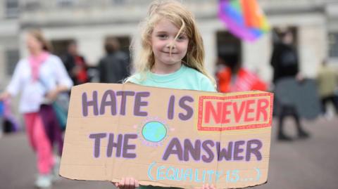 Alana Johnston, five, holds a banner saying hate is never the answer