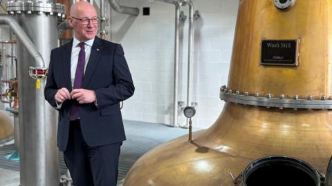 john swinney next to whisky still