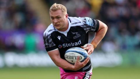 Cameron Hutchinson runs while holding a ball in both hands during a match 
