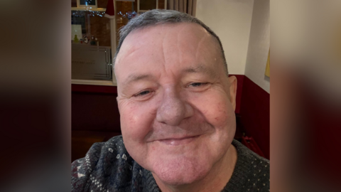  Selfie of Reform UK candidate Andrew Feeney. He is smiling and wearing a patterned jumper - he appears to be in a pub.