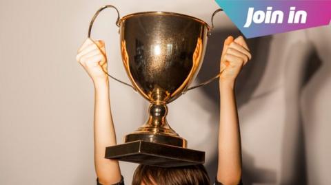 A boy holding a gold trophy above his head.