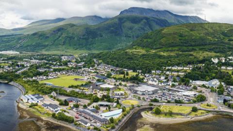 An aerial view of the town on the shores of Loch Linnhe and mountains in the background.