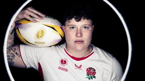 Hannah Botterman in her England rugby strip with a rugby ball on her shoulder