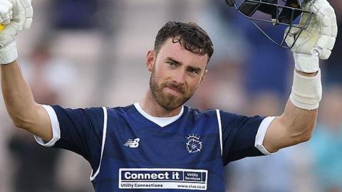 Joe Weatherley holds his bat and helmet up.