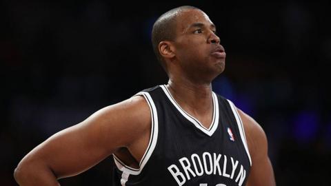 Jason Collins is seen playing for the Brooklyn Nets. He is wearing a black NBA jersey and is exhaling 