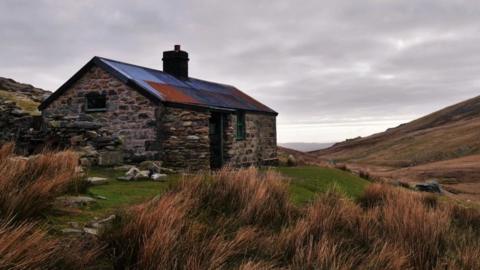 Am antur hynod wyllt mae bwthyn Dulyn yn cynnig cysgod ar lethrau'r Carneddau. Mae'r adeilad yma yn dyddio 'nôl i 1880 pan adeiladwyd argae cyfagos

