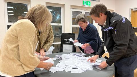 People standing round a table covered in ballot papers