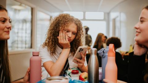 Girl had head in one hand and phone in the other looking bored