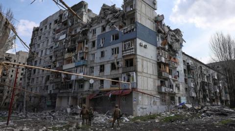 Members of the White Angel unit of Ukrainian police officers stand in front of a destroyed building in Pokrovsk