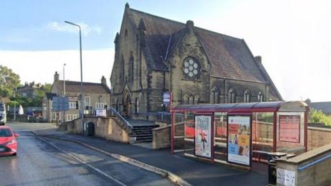 An image of the road shows a red bus stop on the right next to a church. 