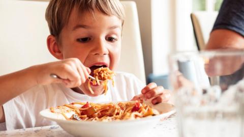 Portrait of boy eating Spaghetti - stock photo