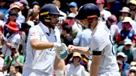 England batter Joe Root (left) and Harry Brook (right) tap gloves
