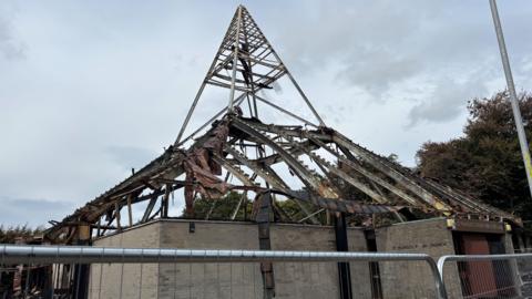St Mungo's Church, blackened and ruined after a bad fire. The church has a pyramid roof, which is wrecked.
