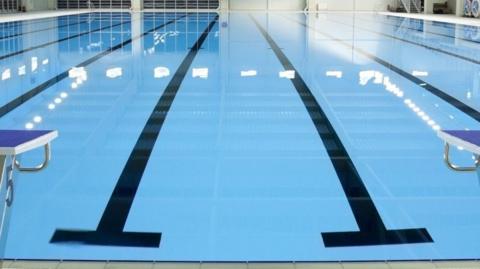 A swimming pool with black strips painted at the bottom of the water