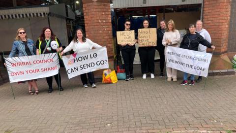 The parents standing outside Birkenhead Market holding signs asking for help for their children