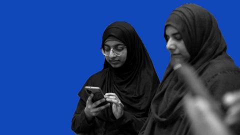 Two ladies look at thir phones.