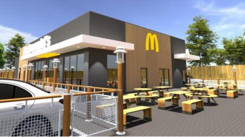 A graphic of how the new McDonald's would look. It is a grey and brown single-storey building with benches outside it. The golden arches are on the wall, as is lettering that reads "McDonald's".