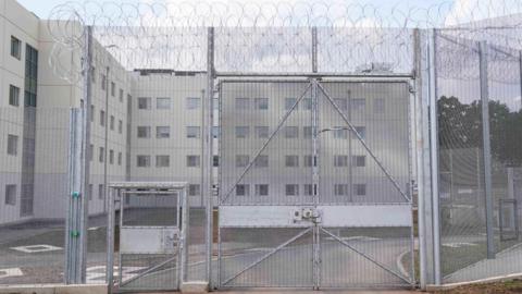 Exterior shot of HMP Fosse Way's metal gates.