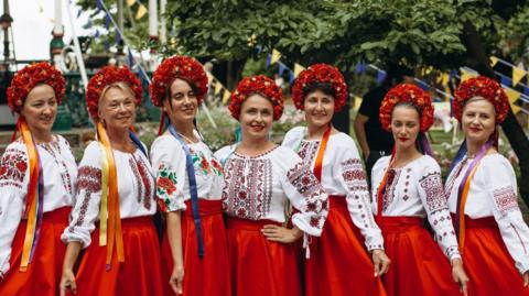 Ukrainian women dressed in red skirts and white decorated tops at last year's UkraineFest. They are also wearing red head dresses.