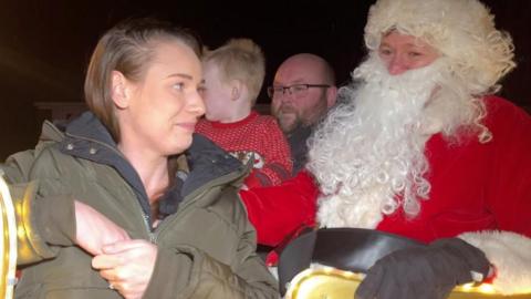 A young family from Burgess Hill sit on Santa's sleigh outside their home.