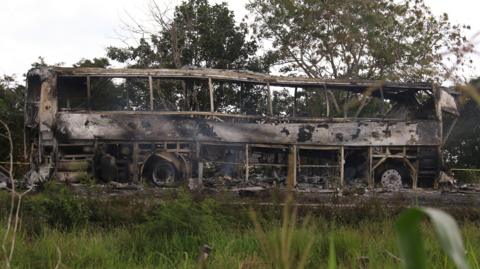 A burned bus is pictured after colliding with a trailer during its journey from Cancun to Tabasco