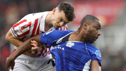 Yakou Meite of Cardiff and Luke McNally of Stoke try and take possession