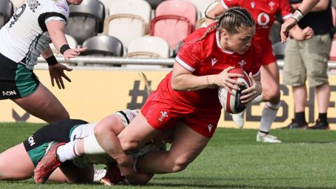 Hannah Bluck of Wales dives to touchdown for a try while being tackled
