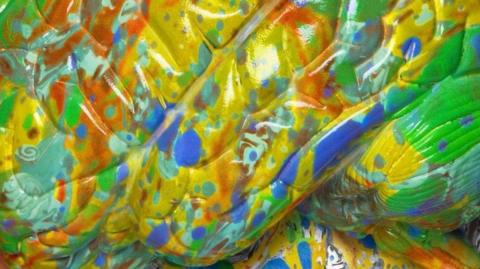 An abstract work of art  with green, yellow and orange irregular shapes and geometric patterns.