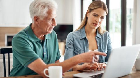 A young woman and her father looking at a laptop